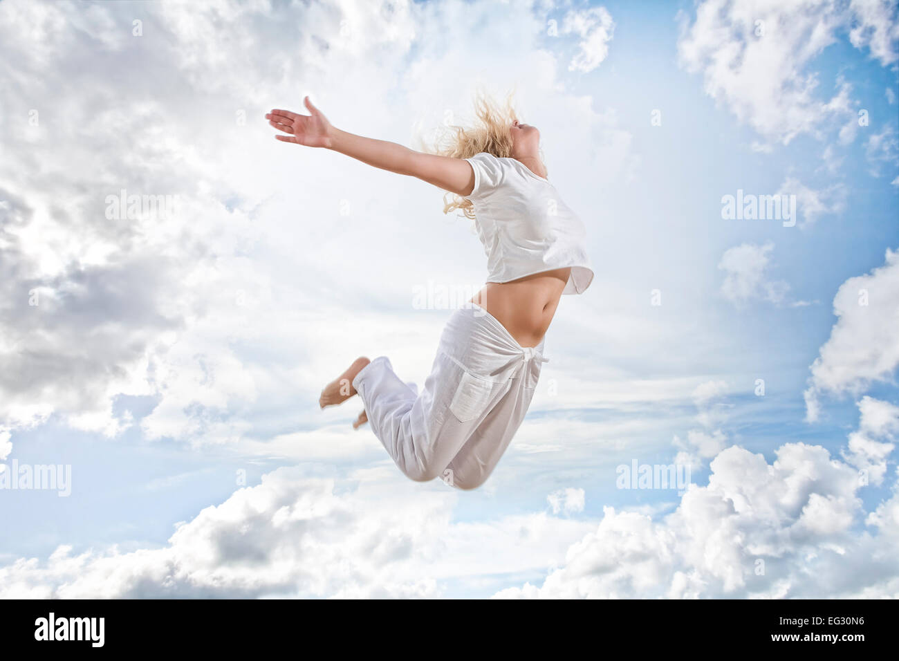 Portrait of young jumping woman on blue sky background Stock Photo - Alamy