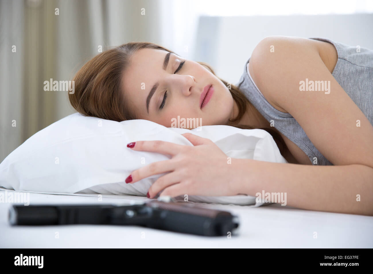 Woman in bed sleeping on the bed with gun Stock Photo Alamy