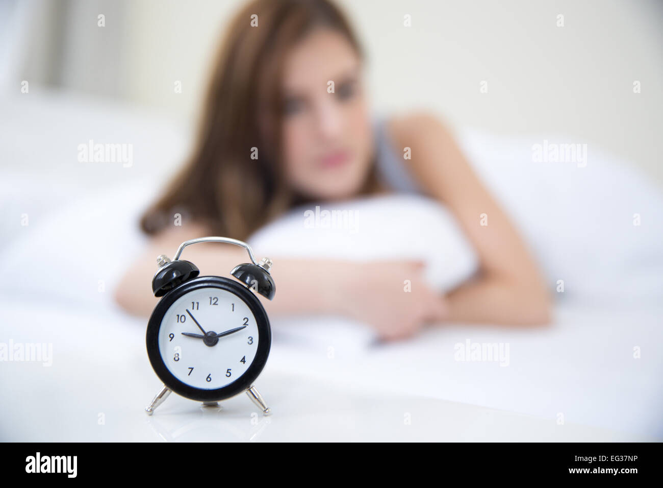 Woman waking up in the morning and looking on alarm clock. Focus on clock Stock Photo