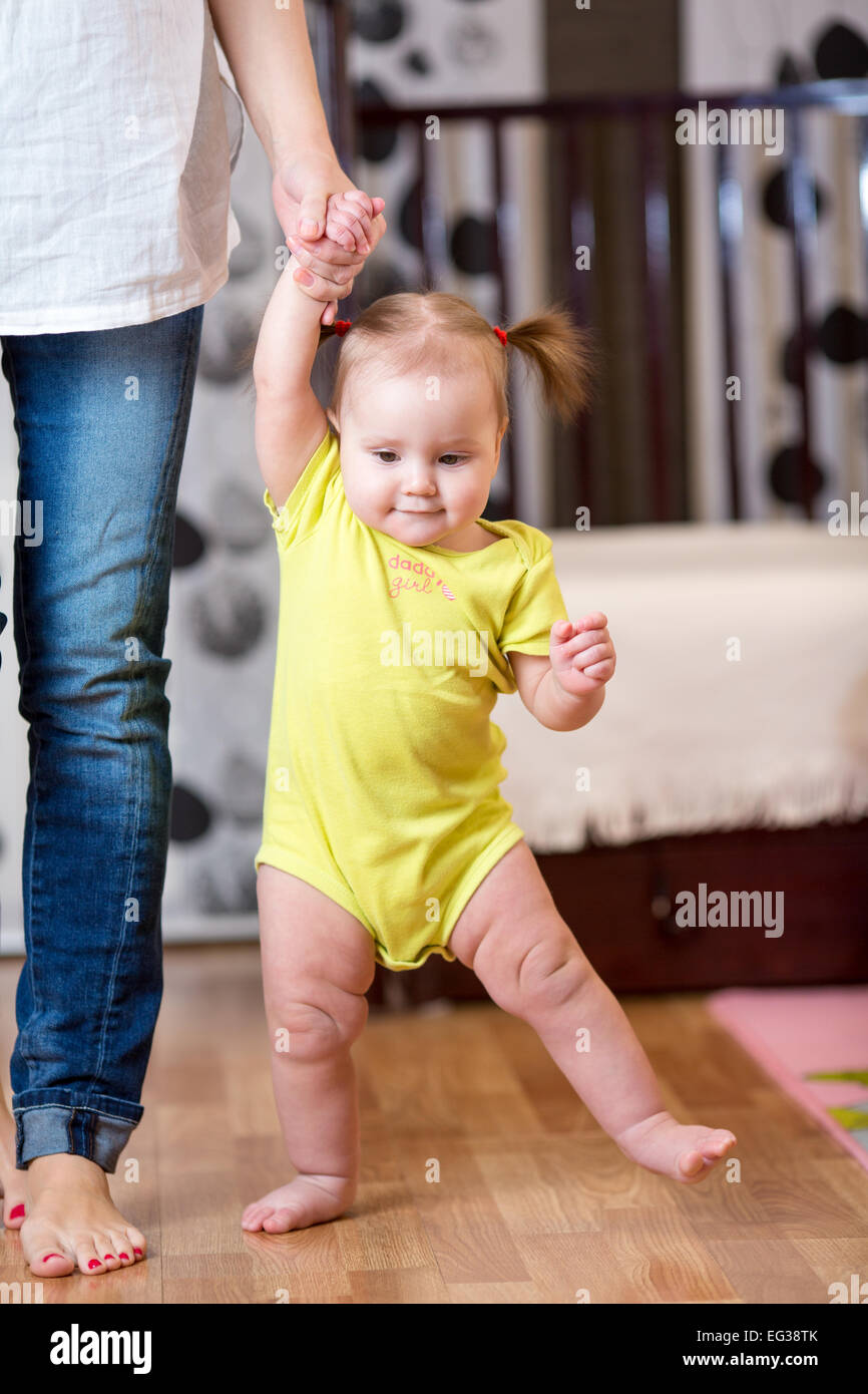 baby taking first steps with mother help Stock Photo