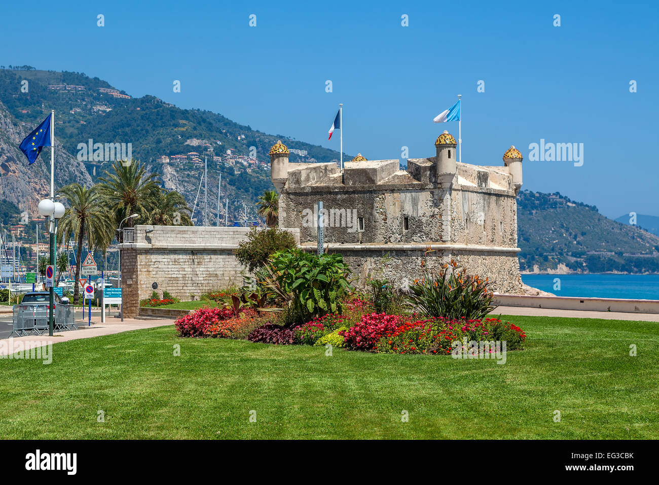 Green grass with flowers on promenade and medieval fortress in Menton, France. Stock Photo