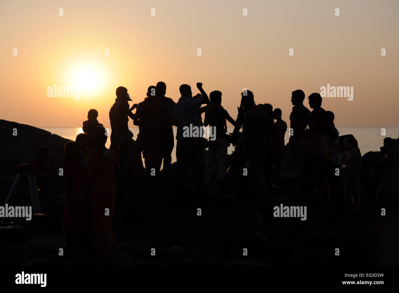 Silhouette of group of people dancing at sunset near the sea Stock Photo