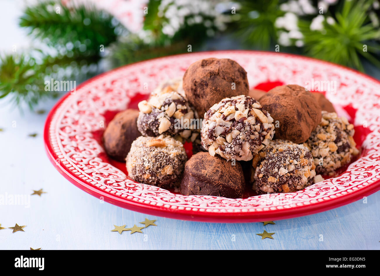 Assorted dark chocolate truffles on red plate, festive decorations, selective focus Stock Photo