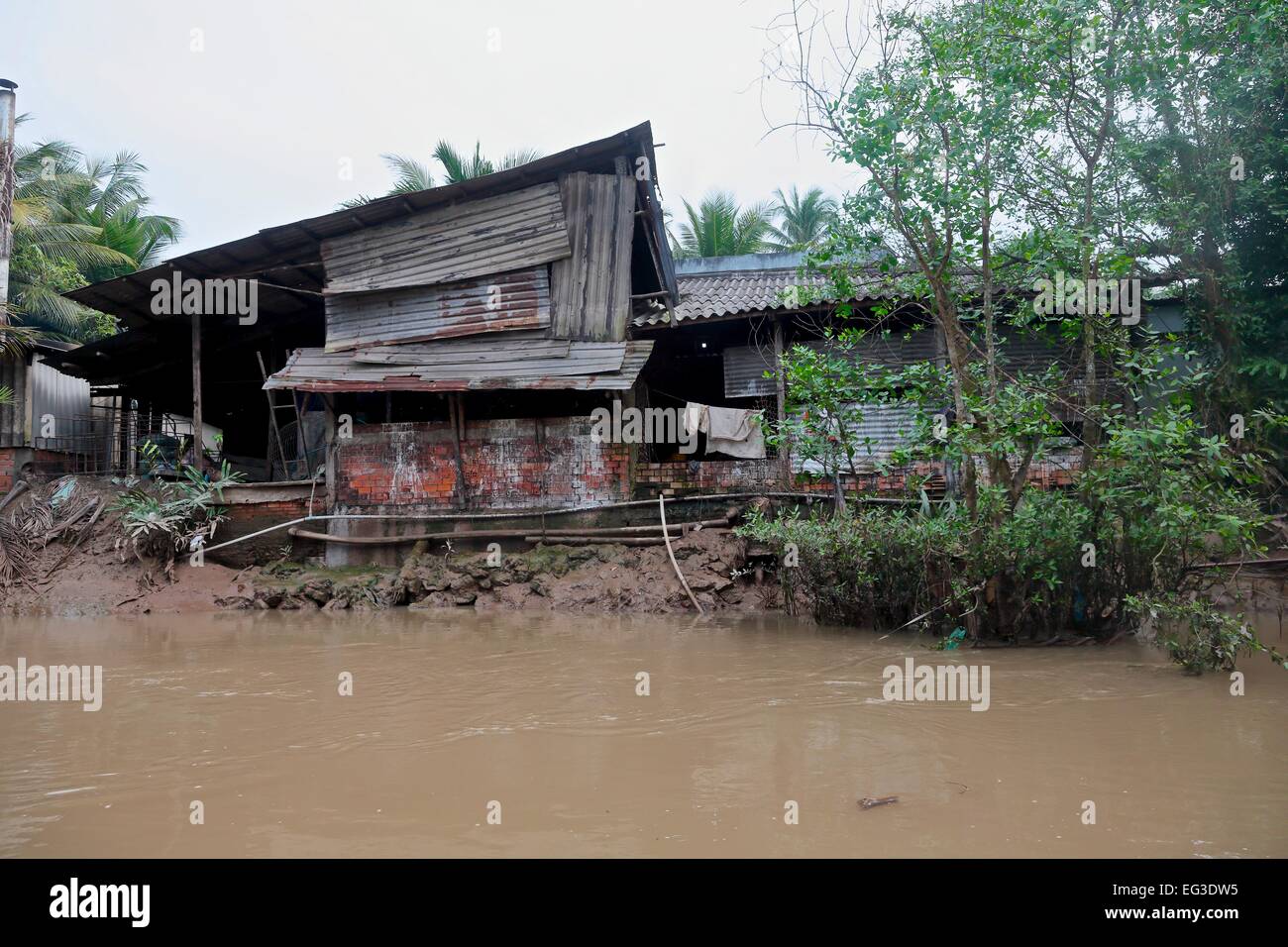 Brick and corrugated iron building the banks of a river in Ben Tre in the Mekong Delta, Vietnam Stock Photo
