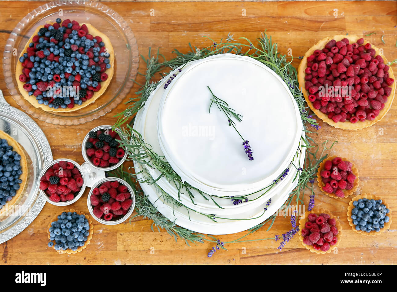 Wedding cake on wooden background with blueberries raspberries and lavender decoration Stock Photo