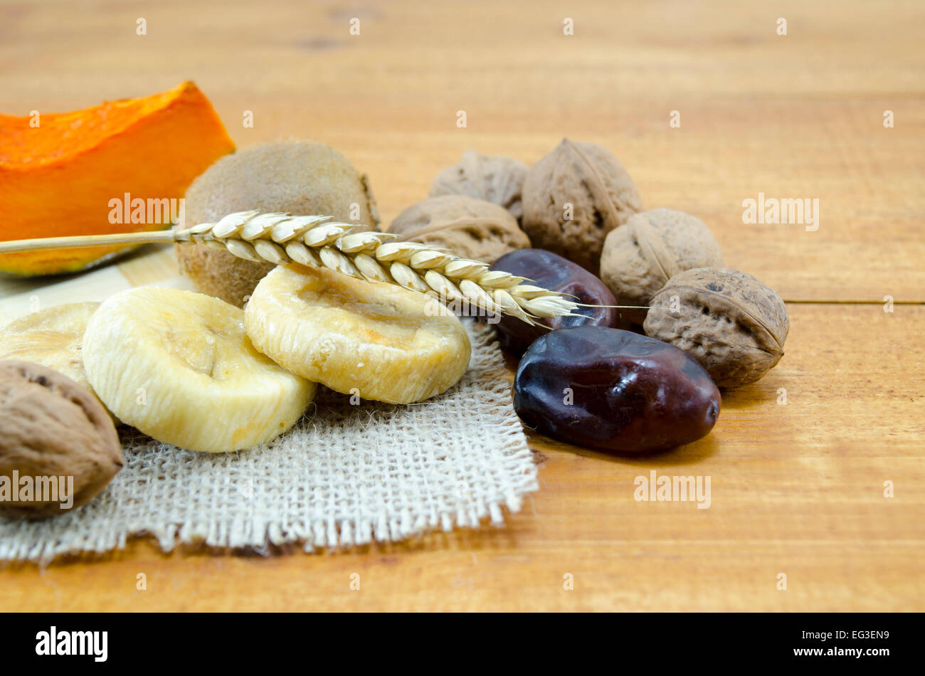 Dried figs, plums, pumpkins with walnuts and kiwis on a wooden table Stock Photo