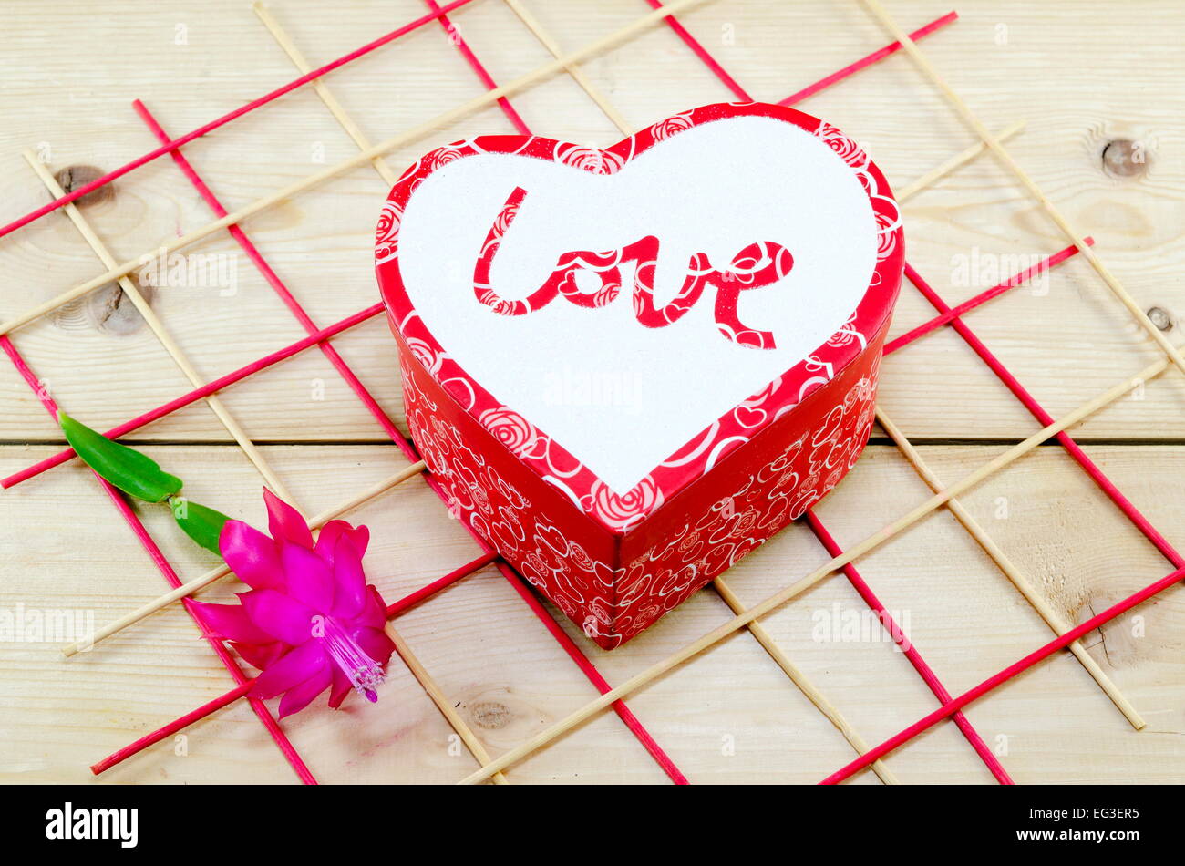 Heart shaped box decorated with a pink flower on a wooden table Stock Photo