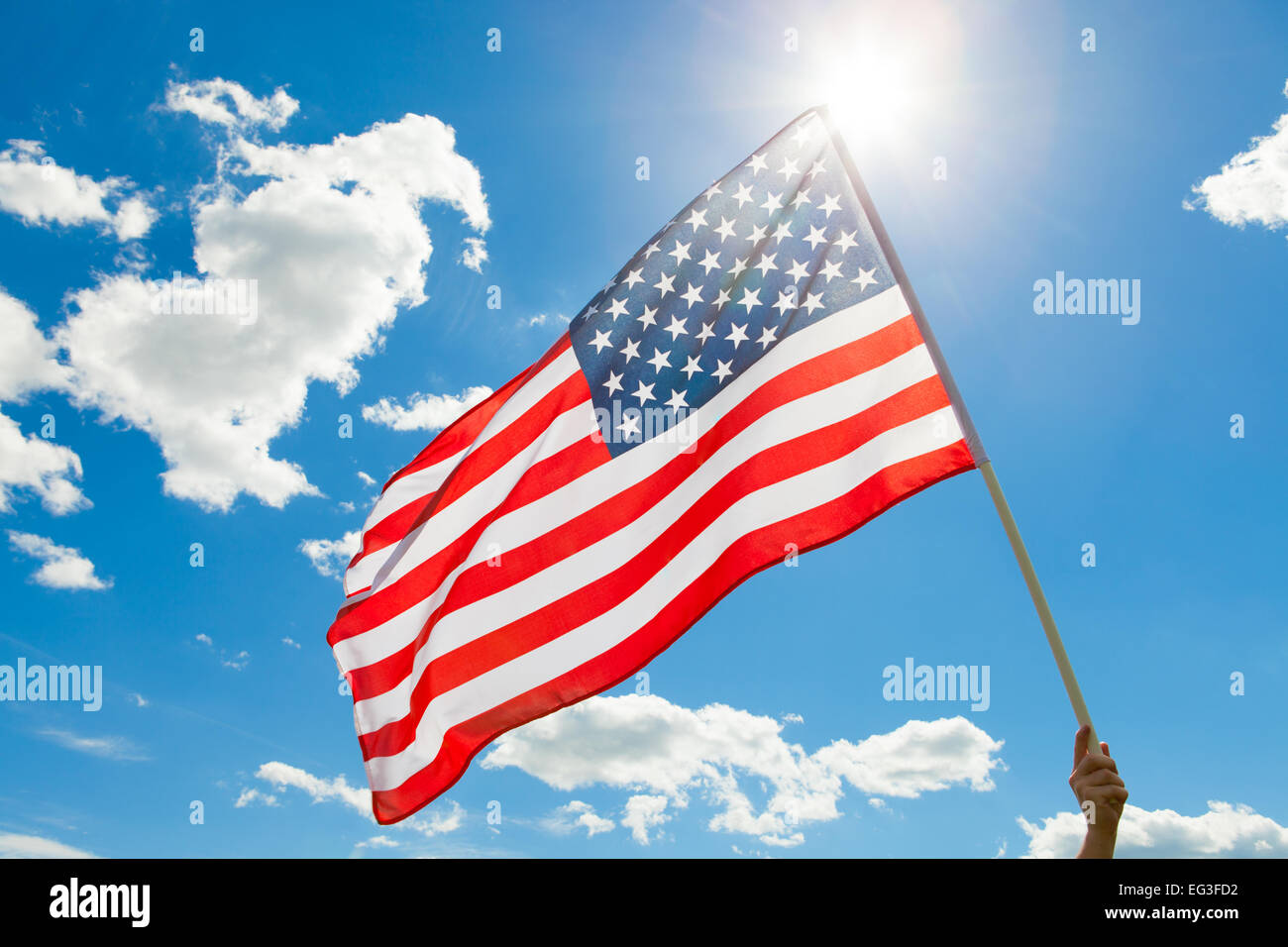 American flag waving in blue sky with sun behind it Stock Photo - Alamy