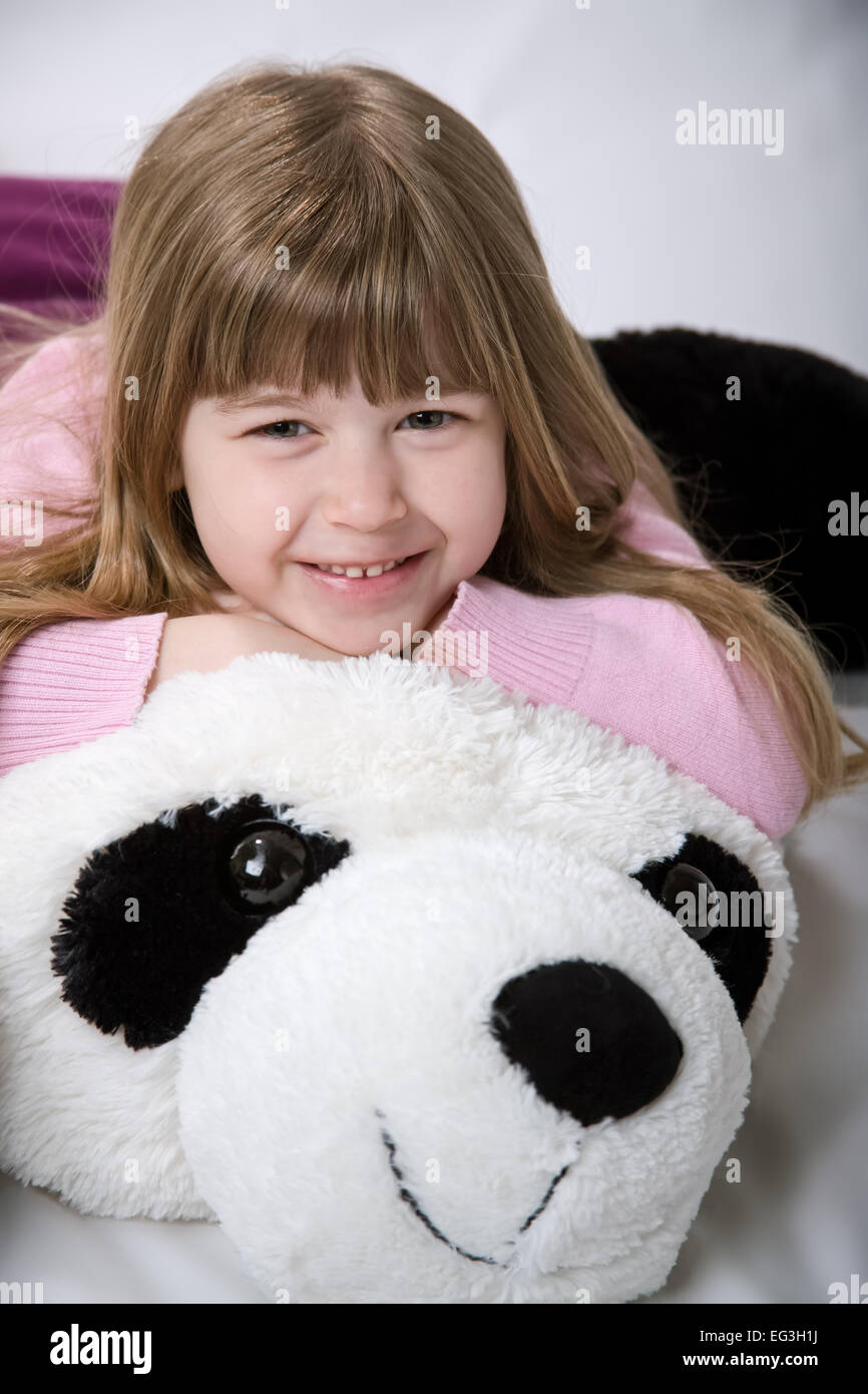 Five year old girl cuddling with a giant, stuffed panda bear Stock