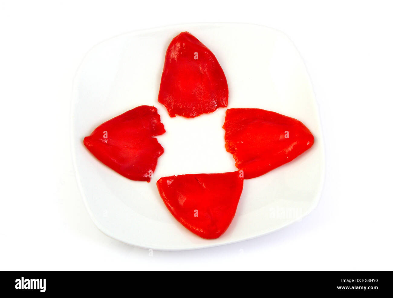 Four roasted red peppers in olive oil on a white dish Stock Photo