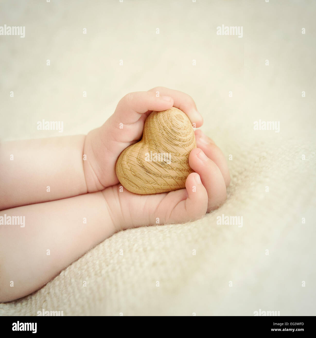 tiny baby hands to hold the wooden heart Stock Photo