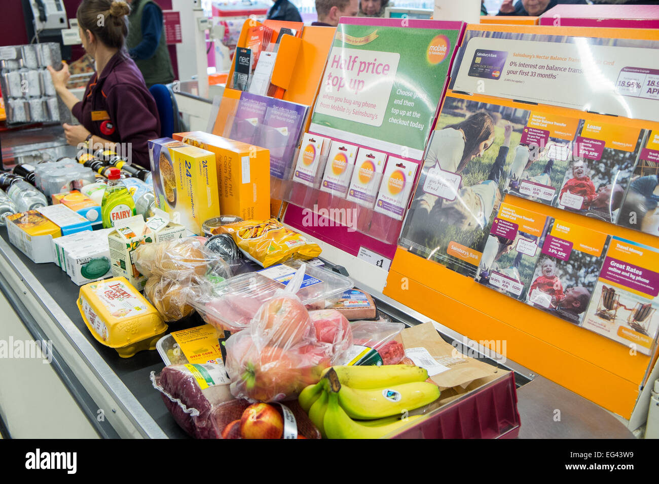 Employee of sainsburys managing the checkout for a customers food