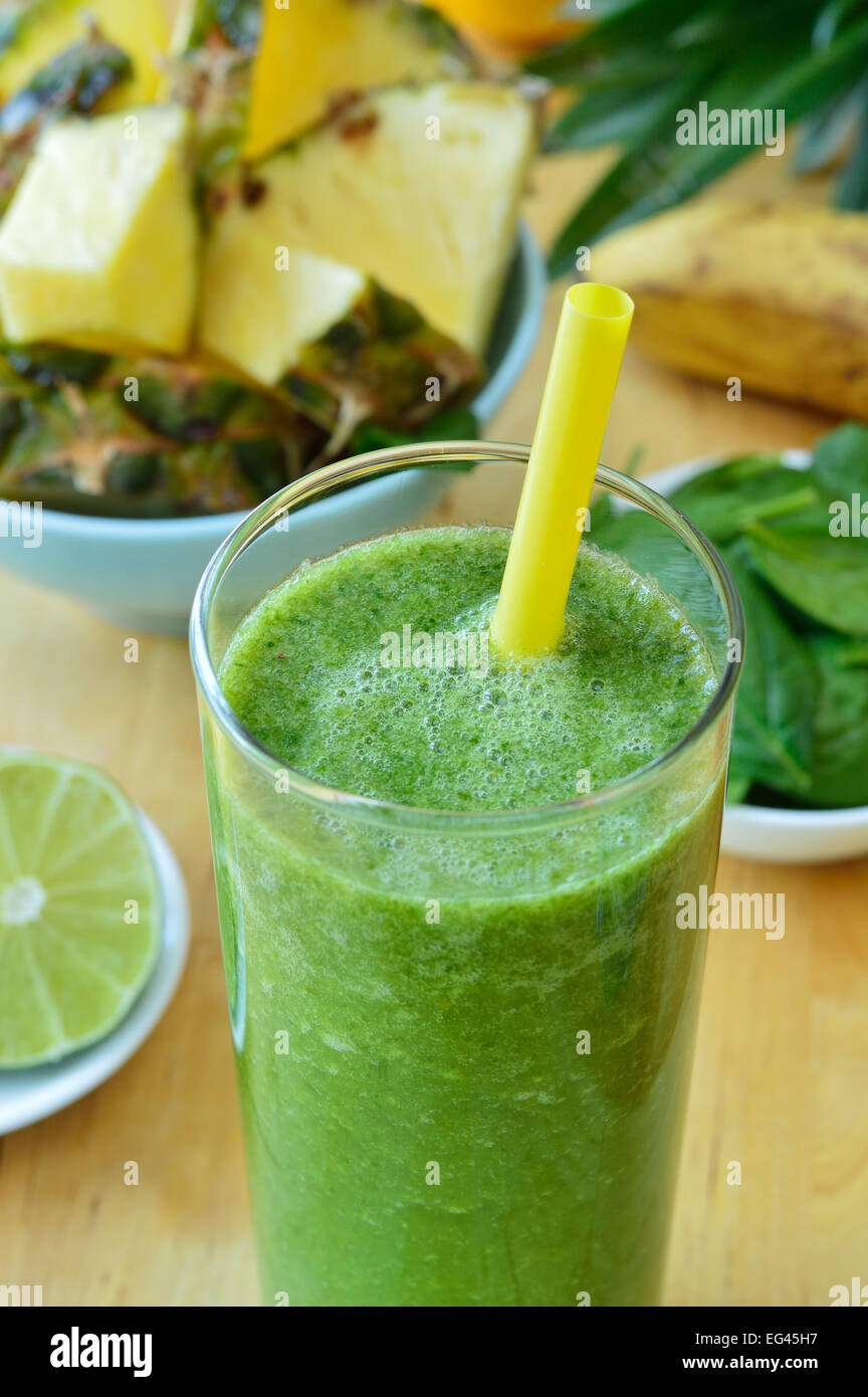 Green spinach and pineapple smoothie on table. Fruit smoothie made with baby spinach leaves
