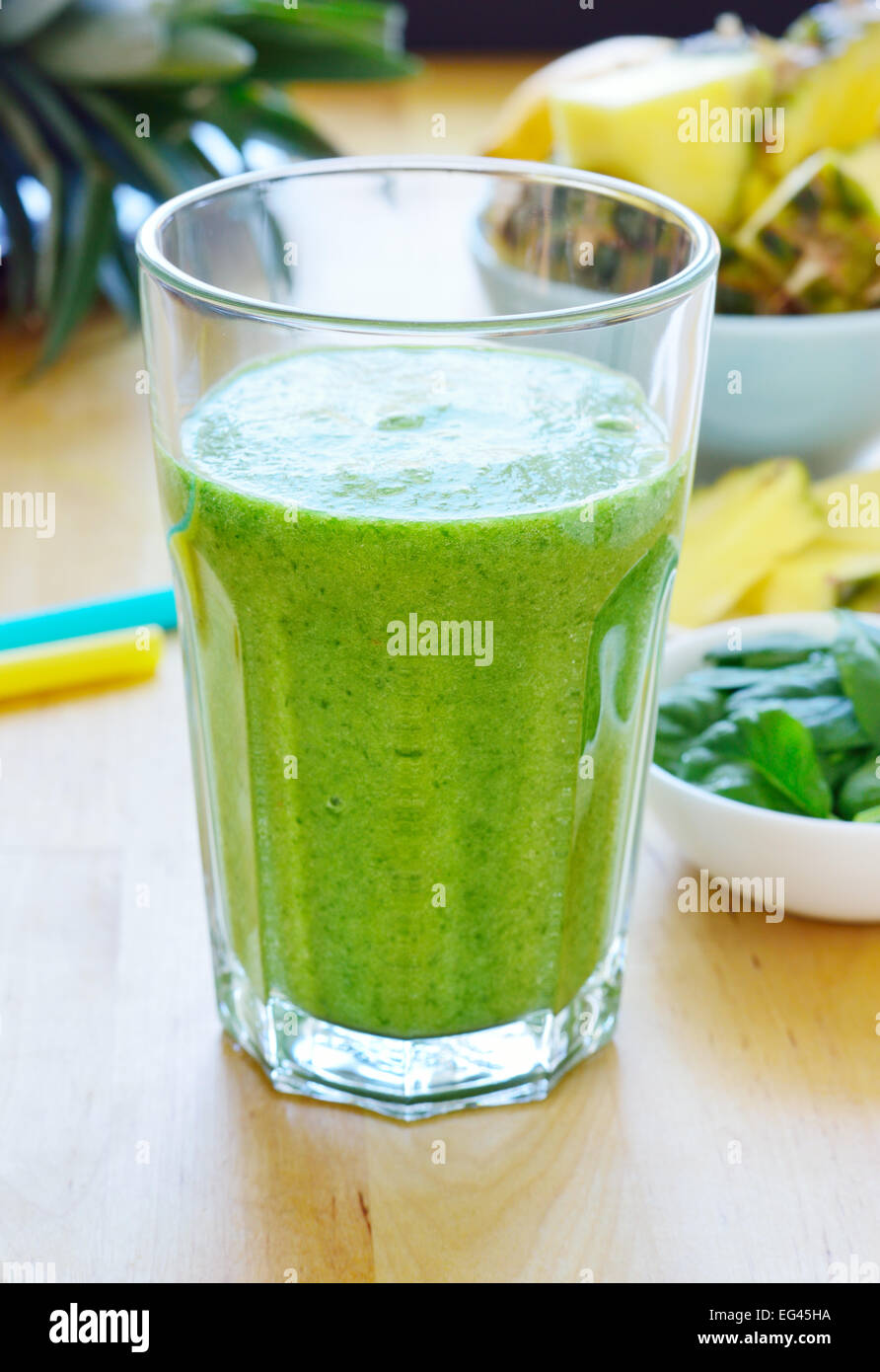 Green spinach and pineapple smoothie on table. Fruit smoothie made with baby spinach leaves