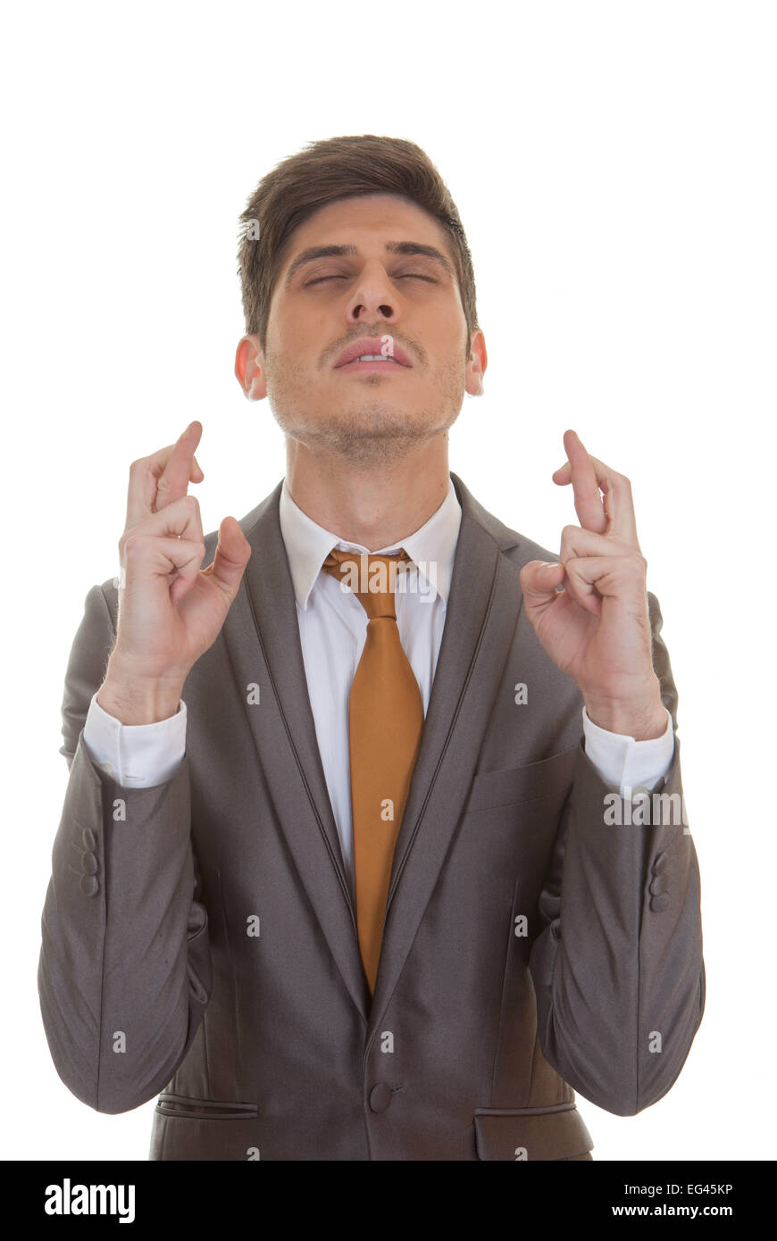 business man fingers crossed eyes closed in hope and optimism Stock