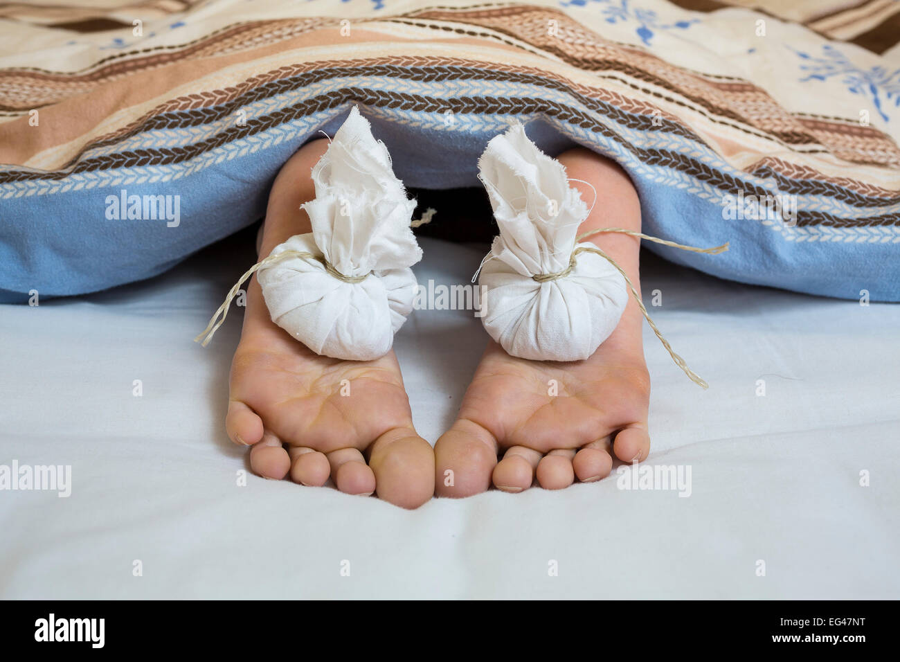 Onion bags on feet, looking out from under a blanket Stock Photo