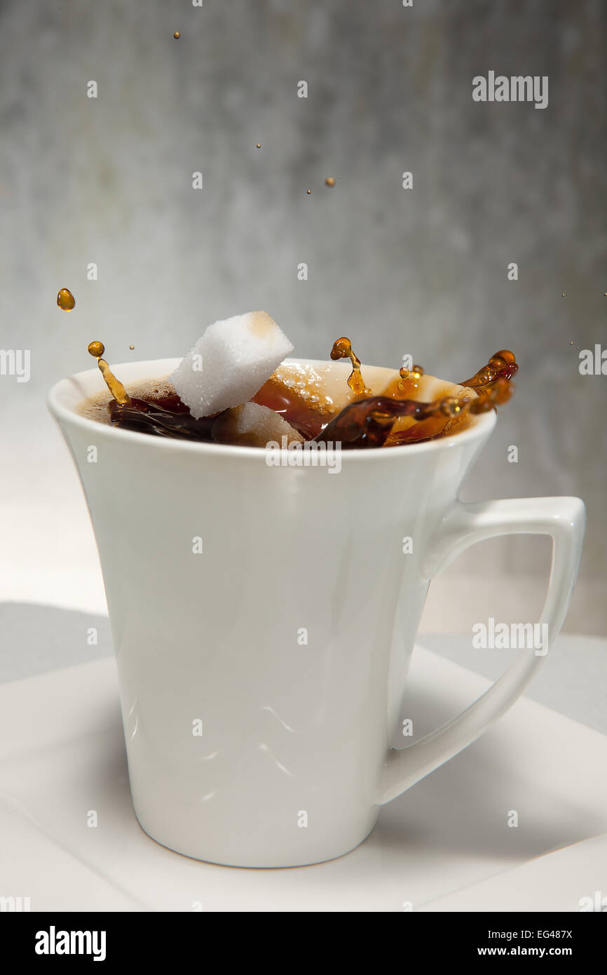 Two sugar cubes falling into a cup of coffee Stock Photo