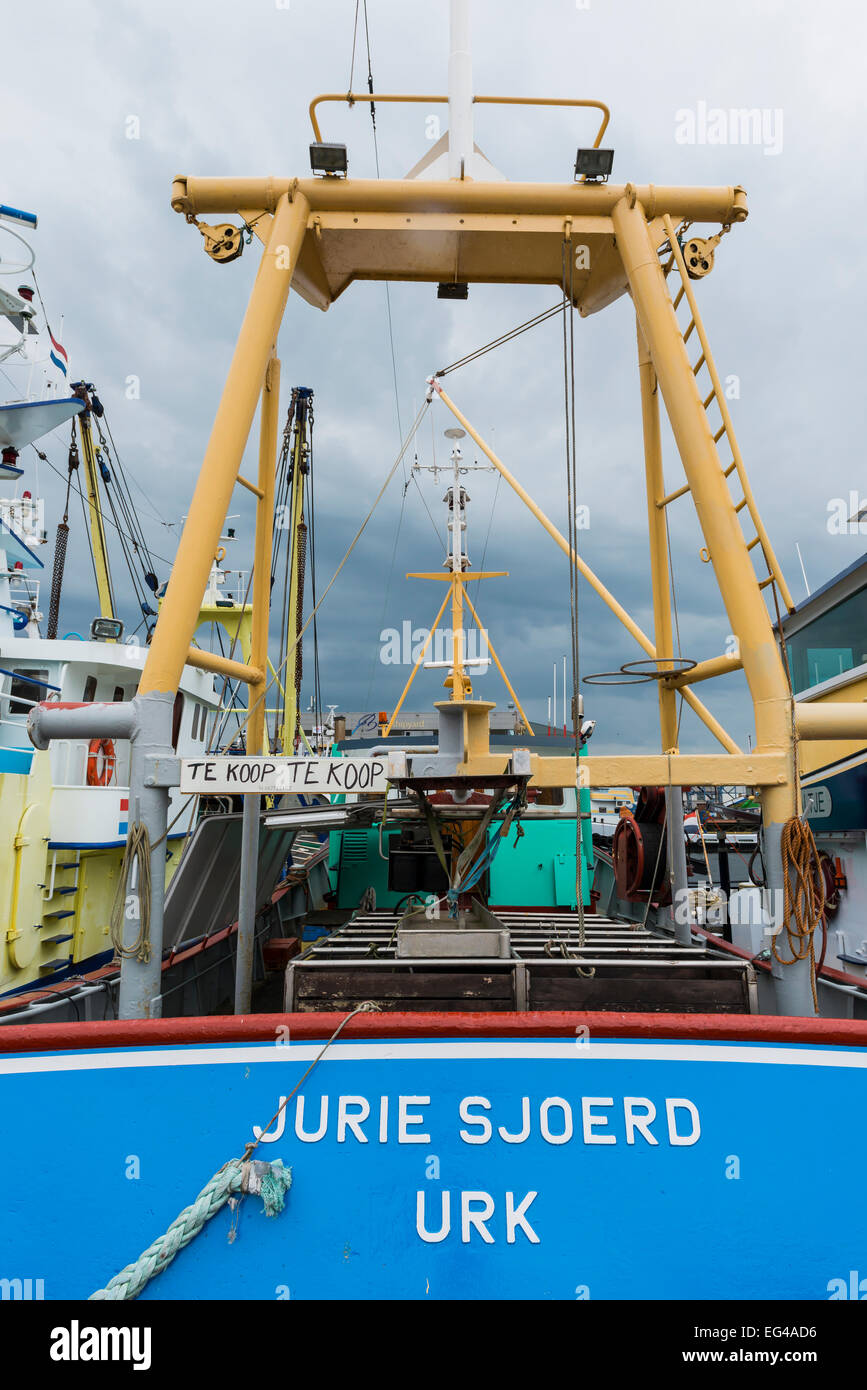 Fishing boat for sale in the harbor of Urk in the Netherlands with dark clouds in the sky. Stock Photo