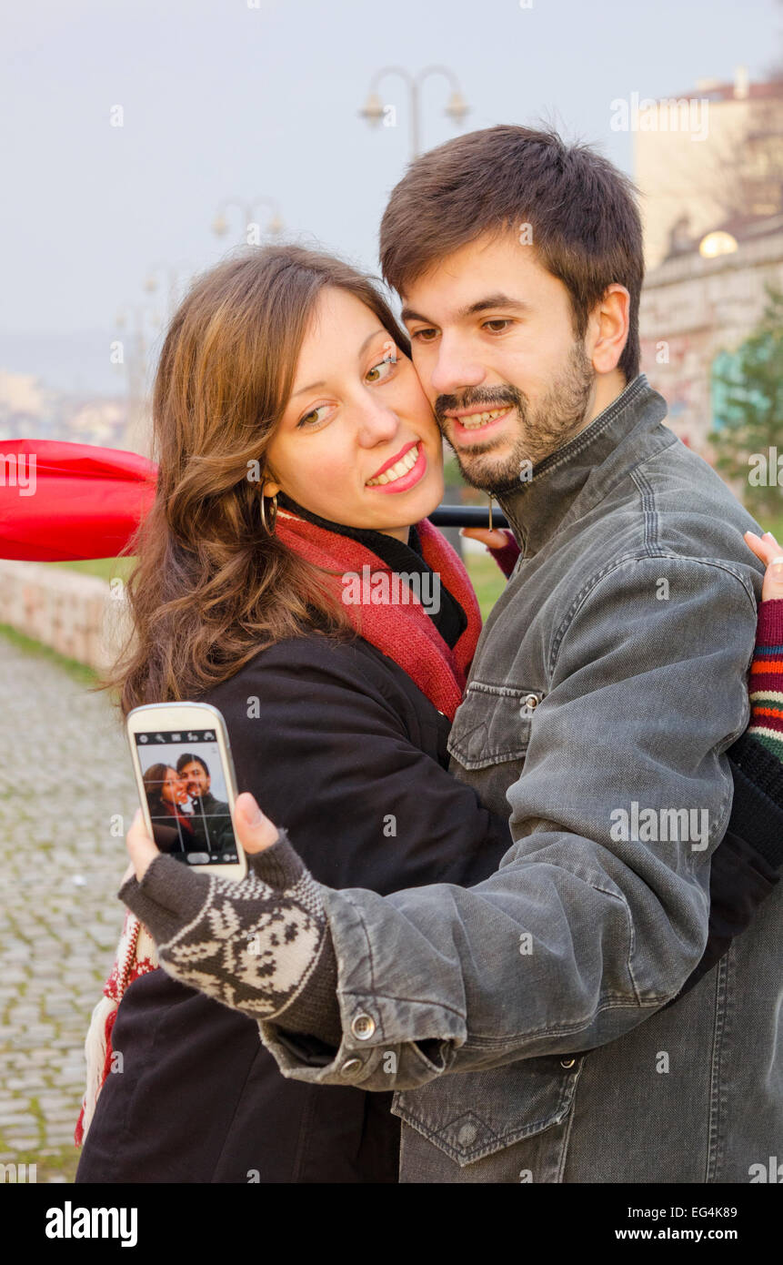 Boy and girl taking a selfie on a rainy day outdoors Stock Photo
