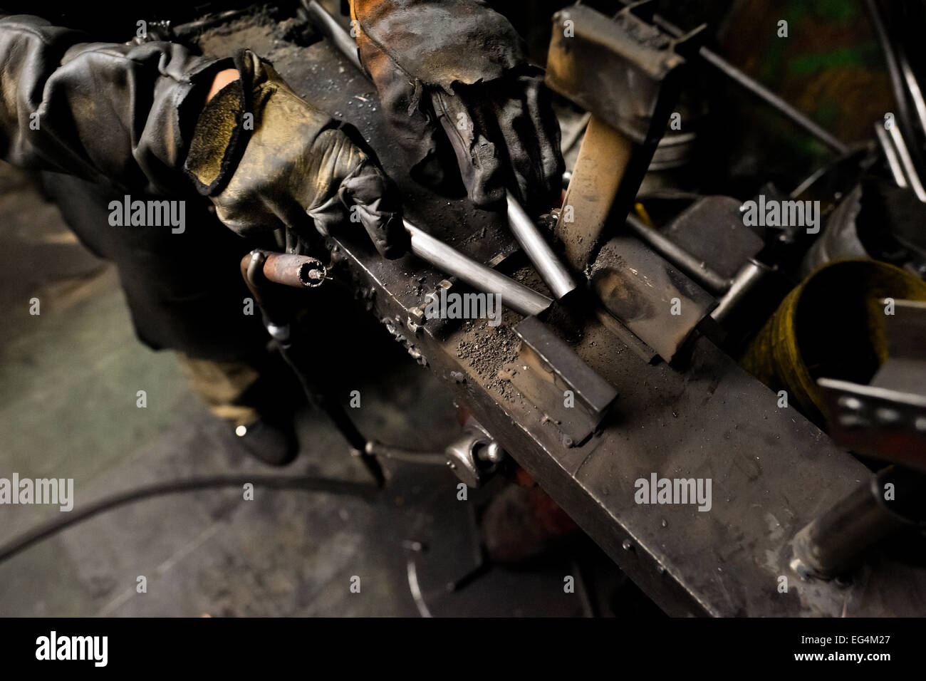 A bicycle welder fixes metal tubes on a welding jig in a small scale