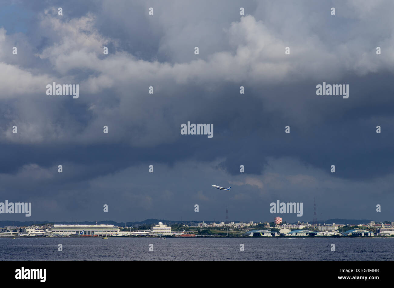 Naha Airport as seen from sea with a departing ANA plane during approaching typhoon, Naha, Okinawa, Japan Stock Photo