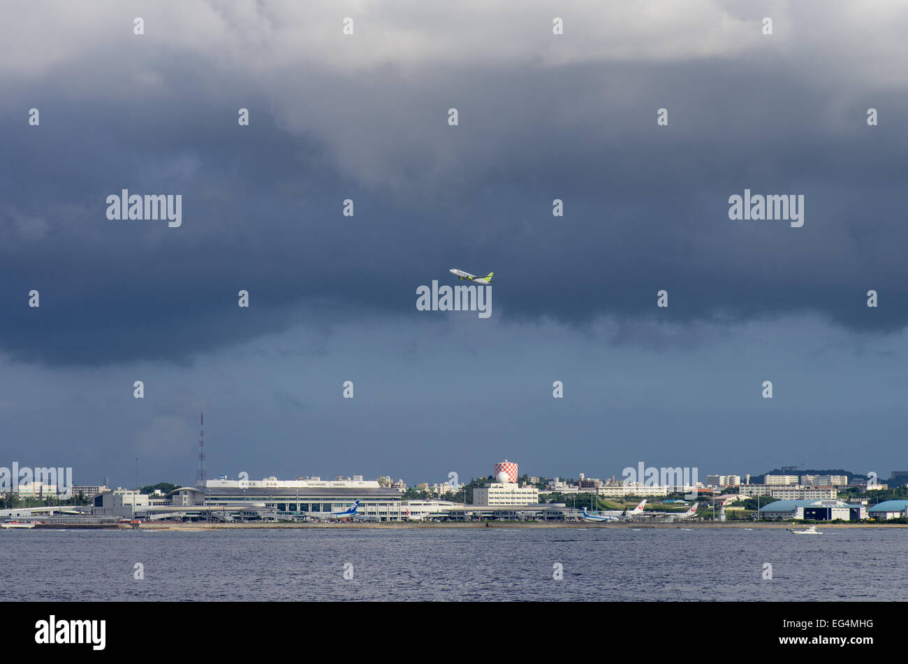 Naha Airport as seen from sea with a departing Solarseed plane during approaching typhoon, Naha, Okinawa, Japan Stock Photo