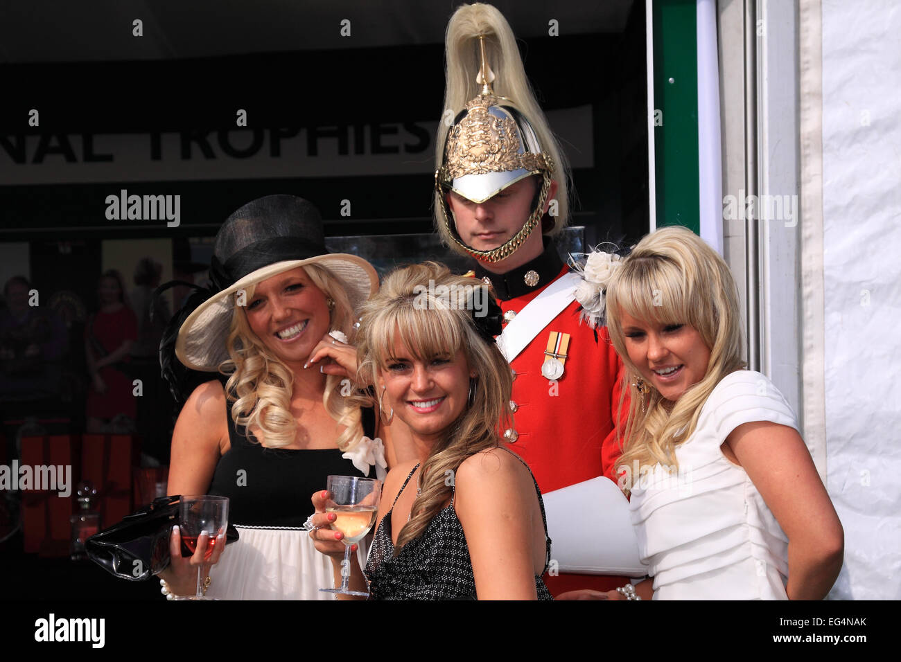 Three ladies pose with one of the uniforms guarding the Grand National Meeting trophies / Ladies Day / Aintree Racecourse Stock Photo
