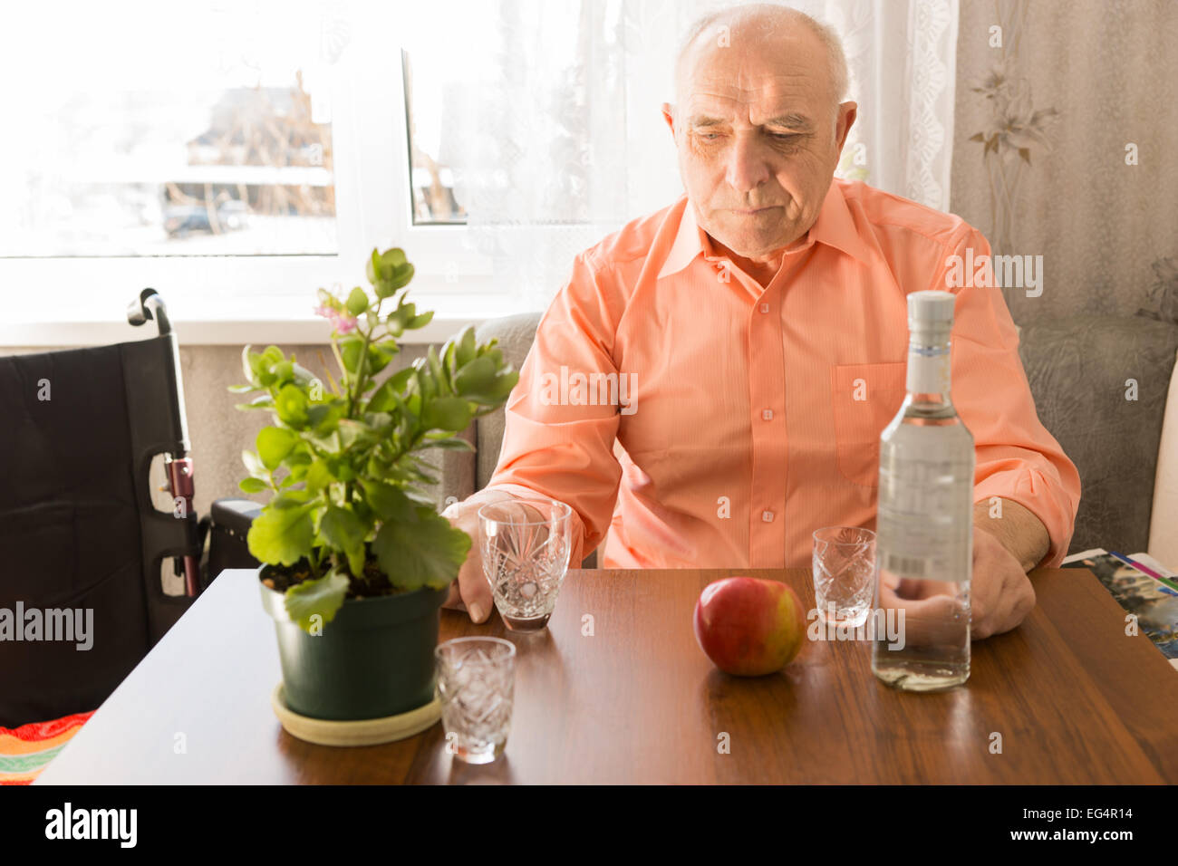 Close up Lonely Sitting Elderly Drinking Wine at the Table with Apple and Green Plant on Top. Stock Photo