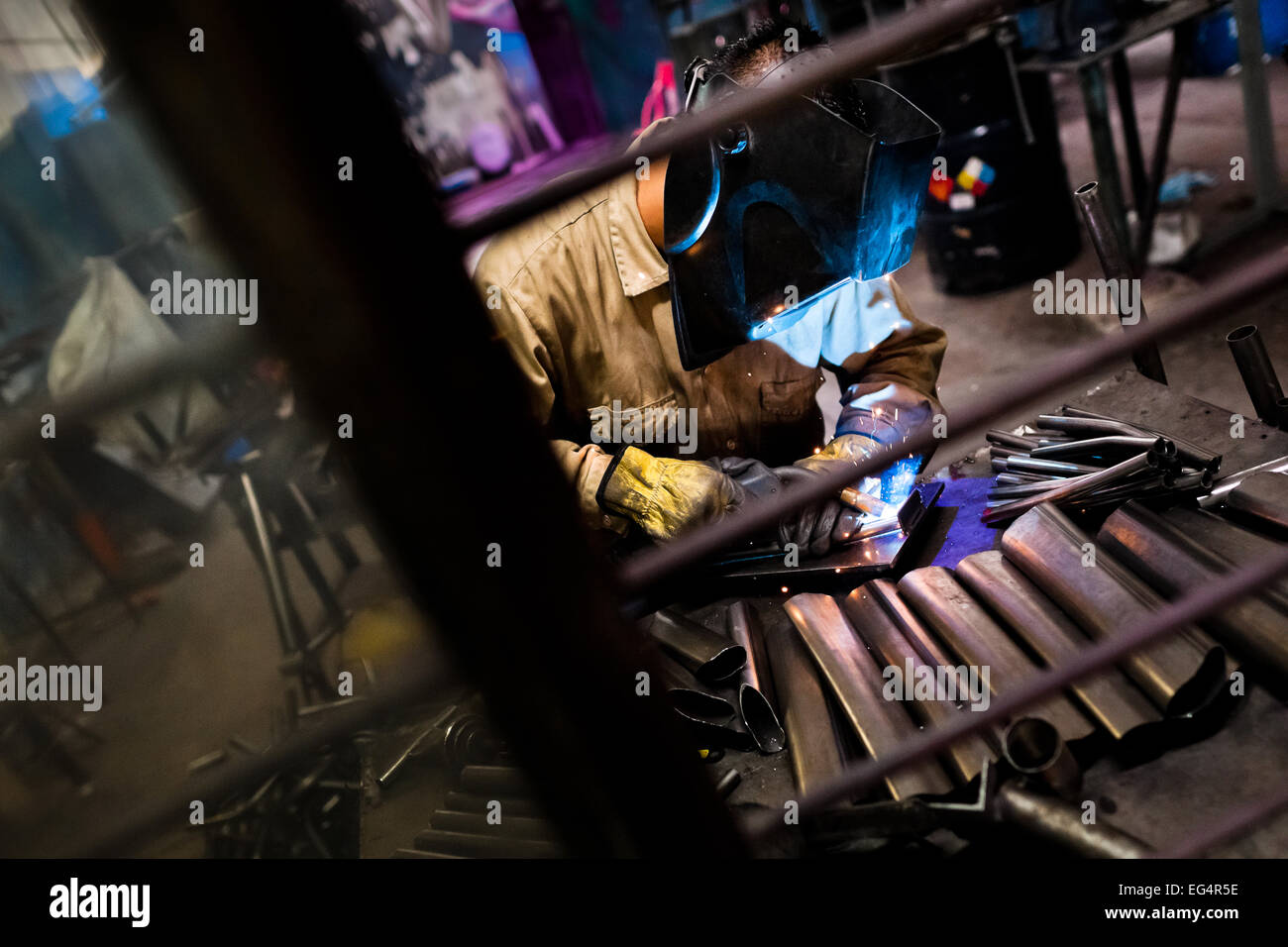 A bicycle welder works on a bike frame fixed on a welding jig in a