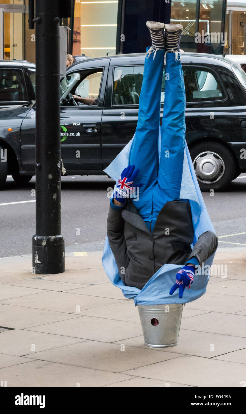 Man upside down with his head in a bucket Stock Photo