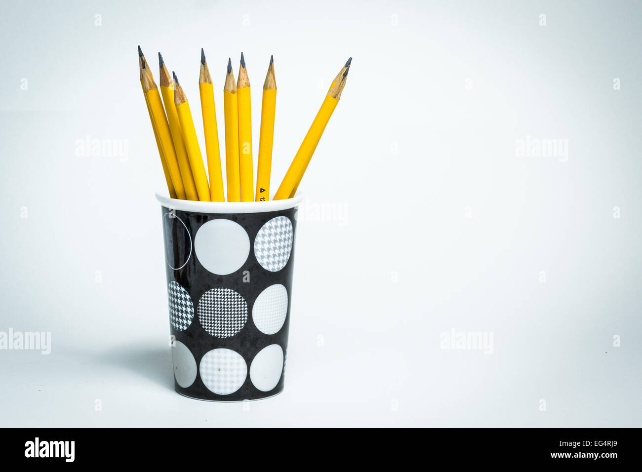 A group of yellow pencils in a cup on a white isolated background Stock Photo