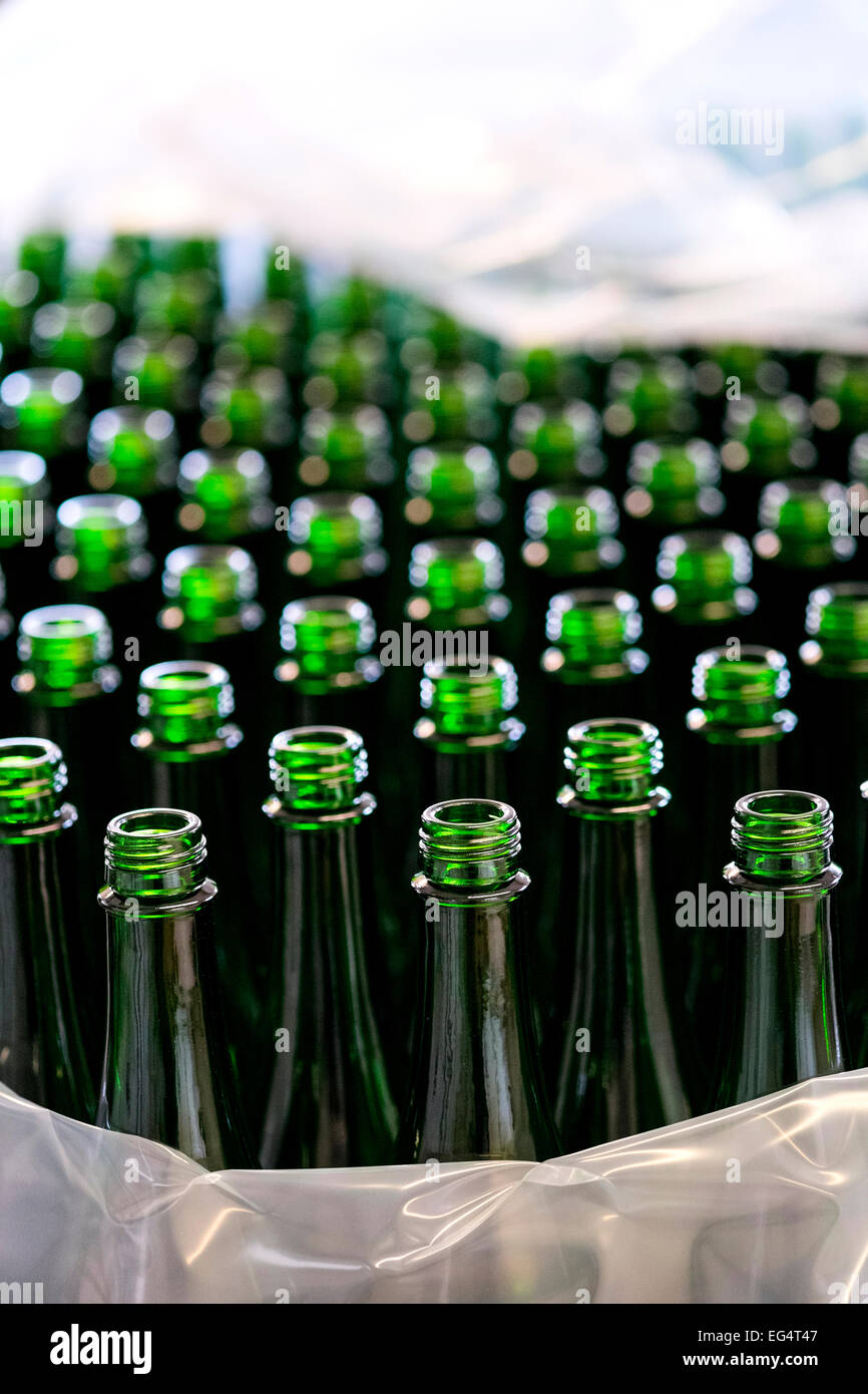 Plastic wrapping and rows of empty green bottles in bottling plant Stock Photo