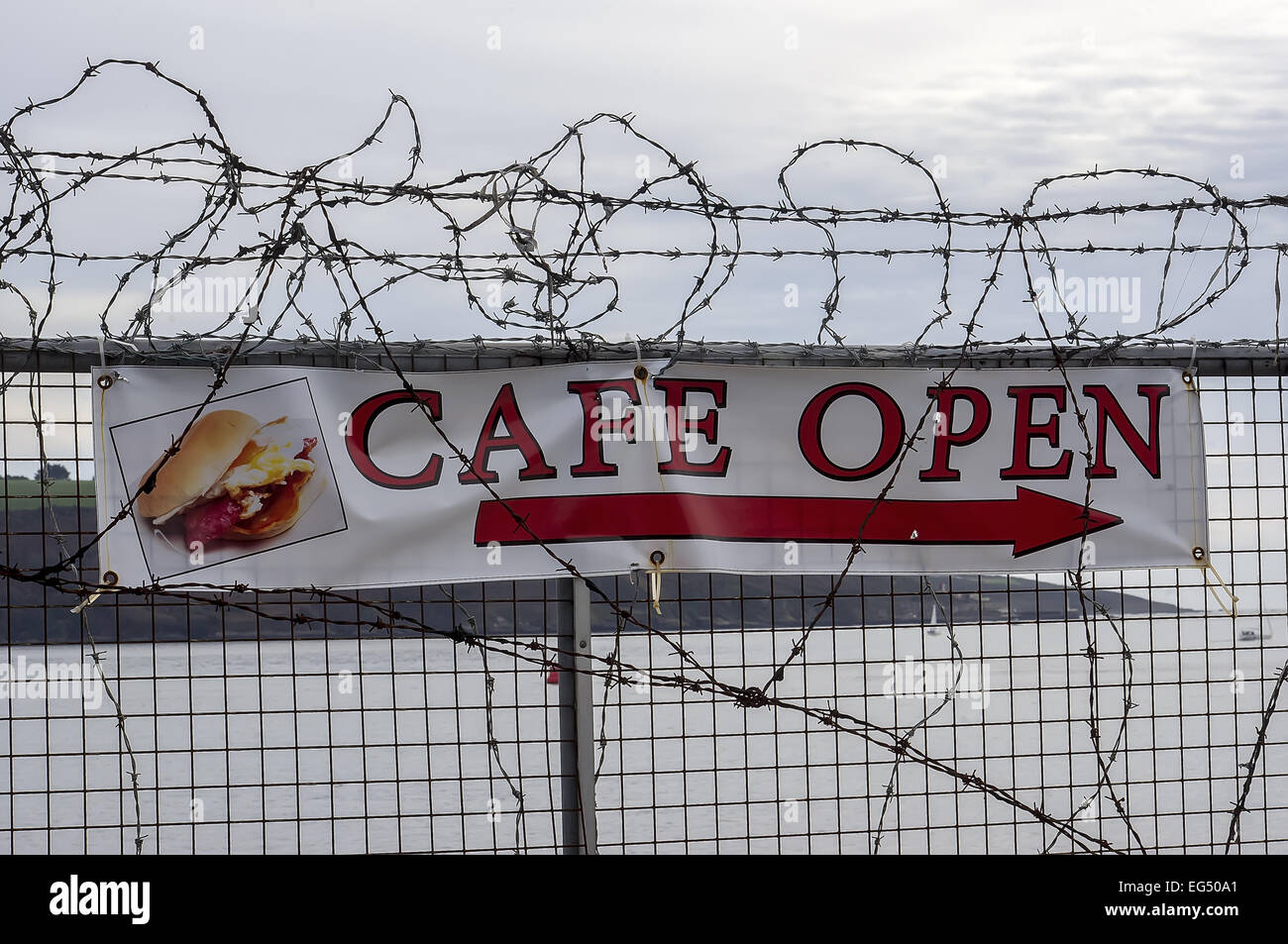 barbed wire,banner, advertising,fence,cafe open,arrow,sea Stock Photo