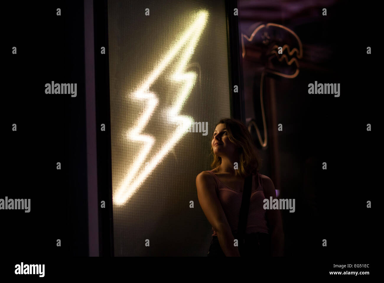 A portrait of a young woman lit by a neon sign Stock Photo