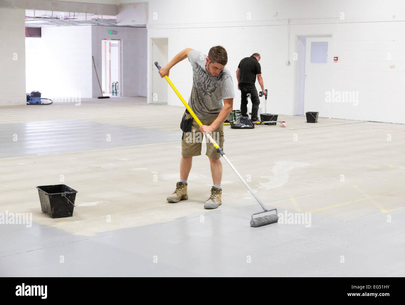 a worker painting a factory floor with epoxy based paint for hard