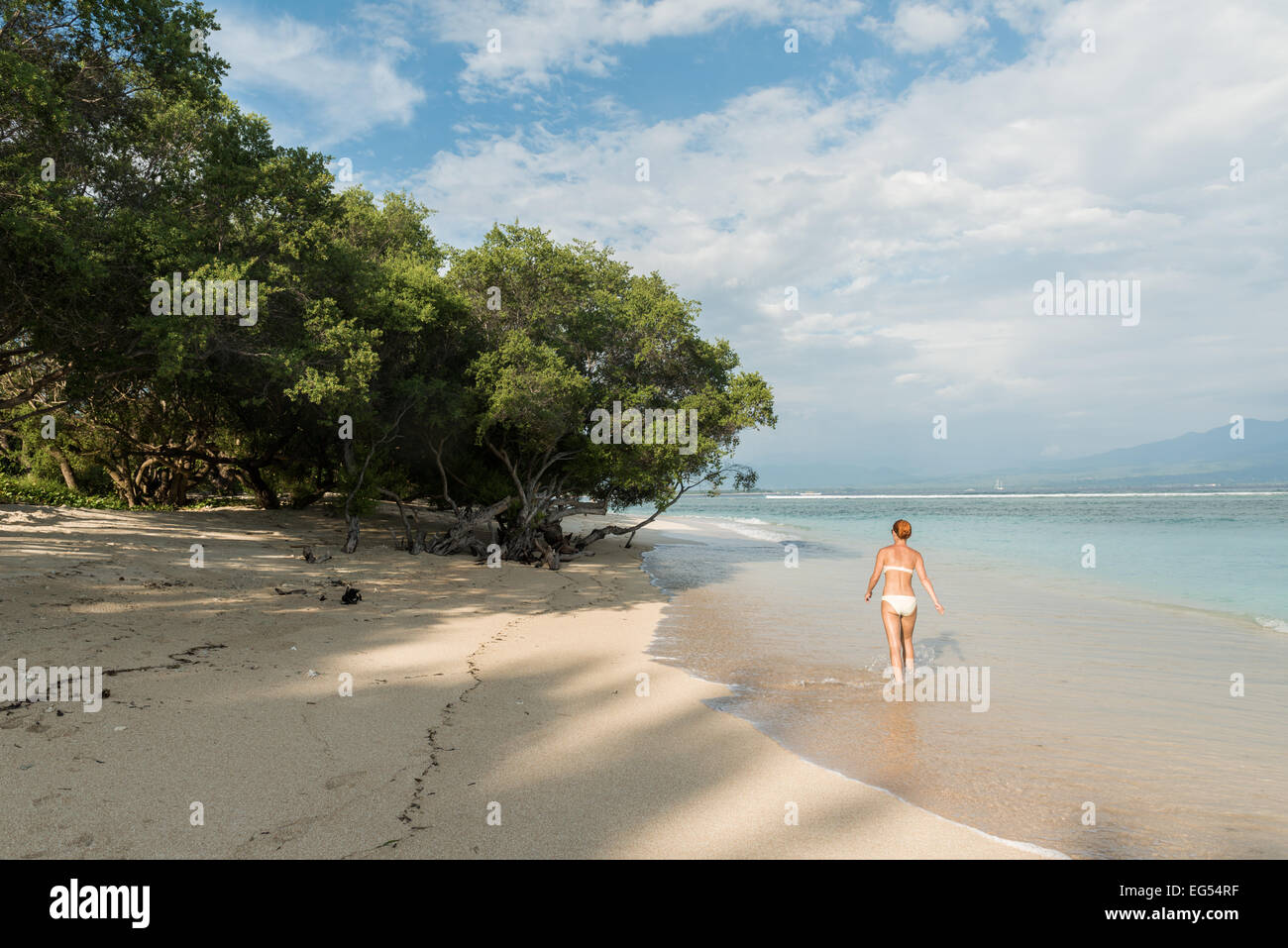 Young woman walking along tropical beach Stock Photo - Alamy