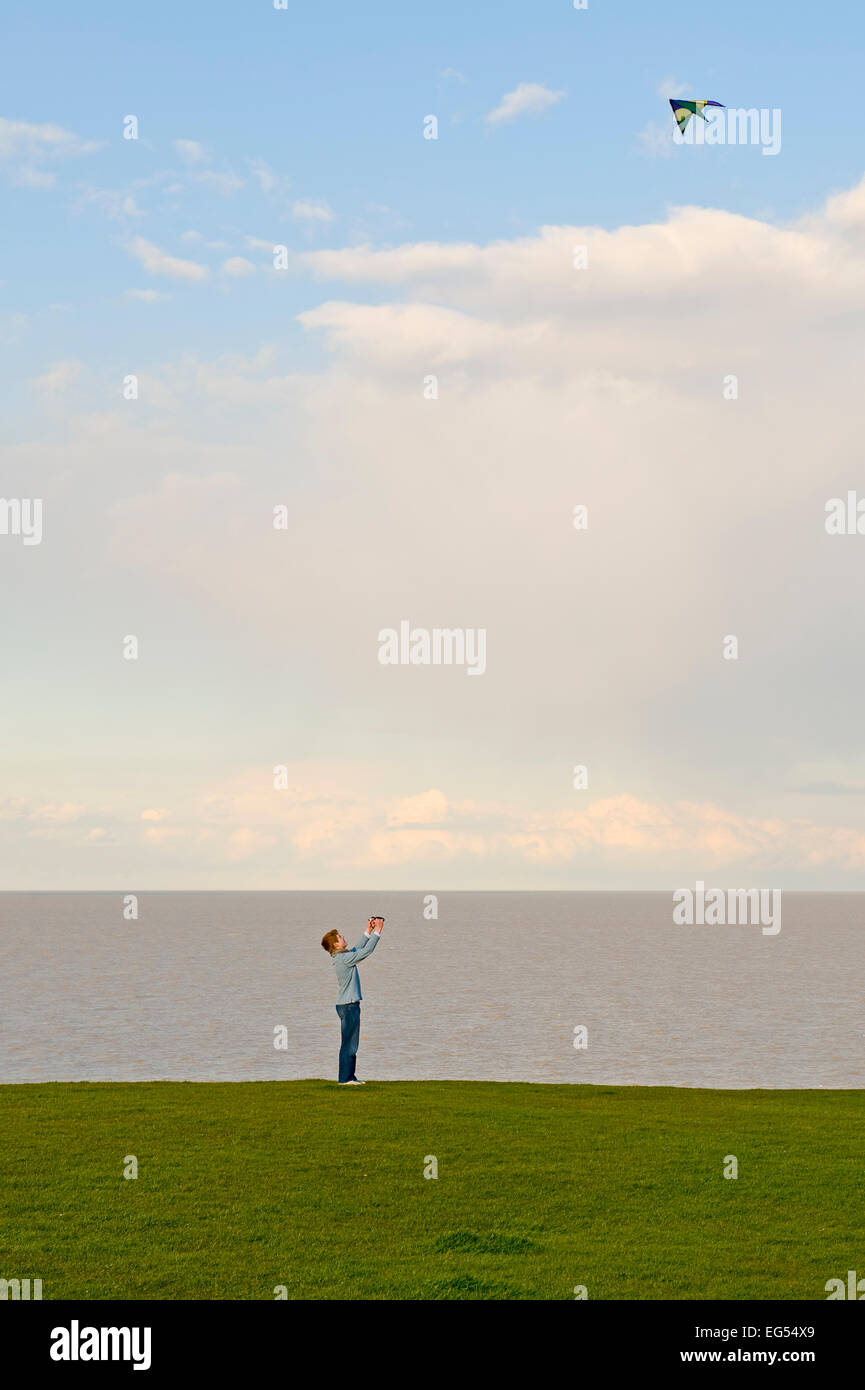 Young male flying a kite on a cliff top at Tankerton Kent England Stock Photo