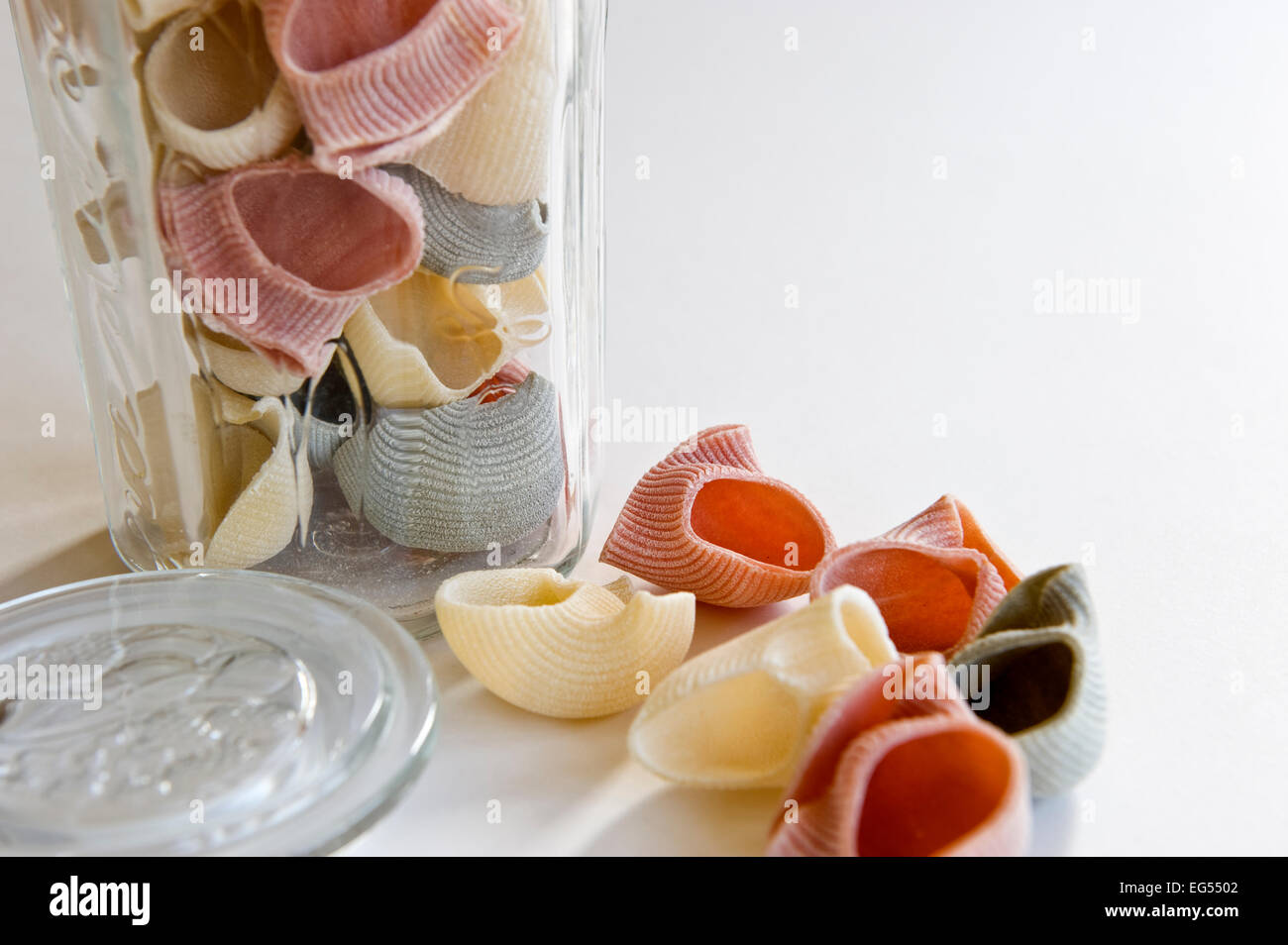 Pasta Shells Color A few scattered coloured pasta shells shown in front of an open glass ...