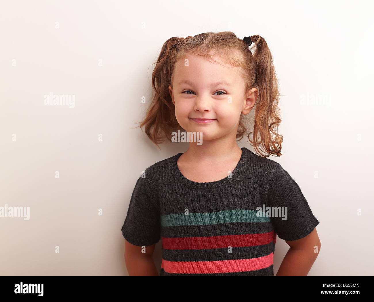 Fun smiling kid girl in dress smiling and looking happy on empty white space background Stock Photo