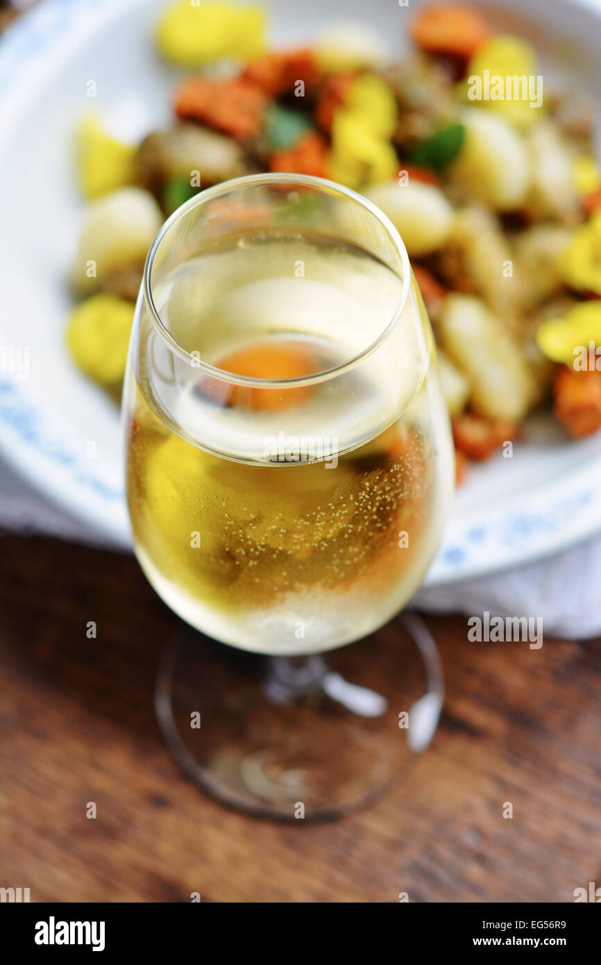 Glass of white wine in front of dish with gnocchi. Stock Photo