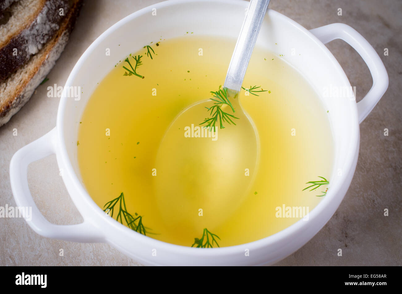 Bouillon, broth, clear soup in a white old bowl with spoon Stock Photo