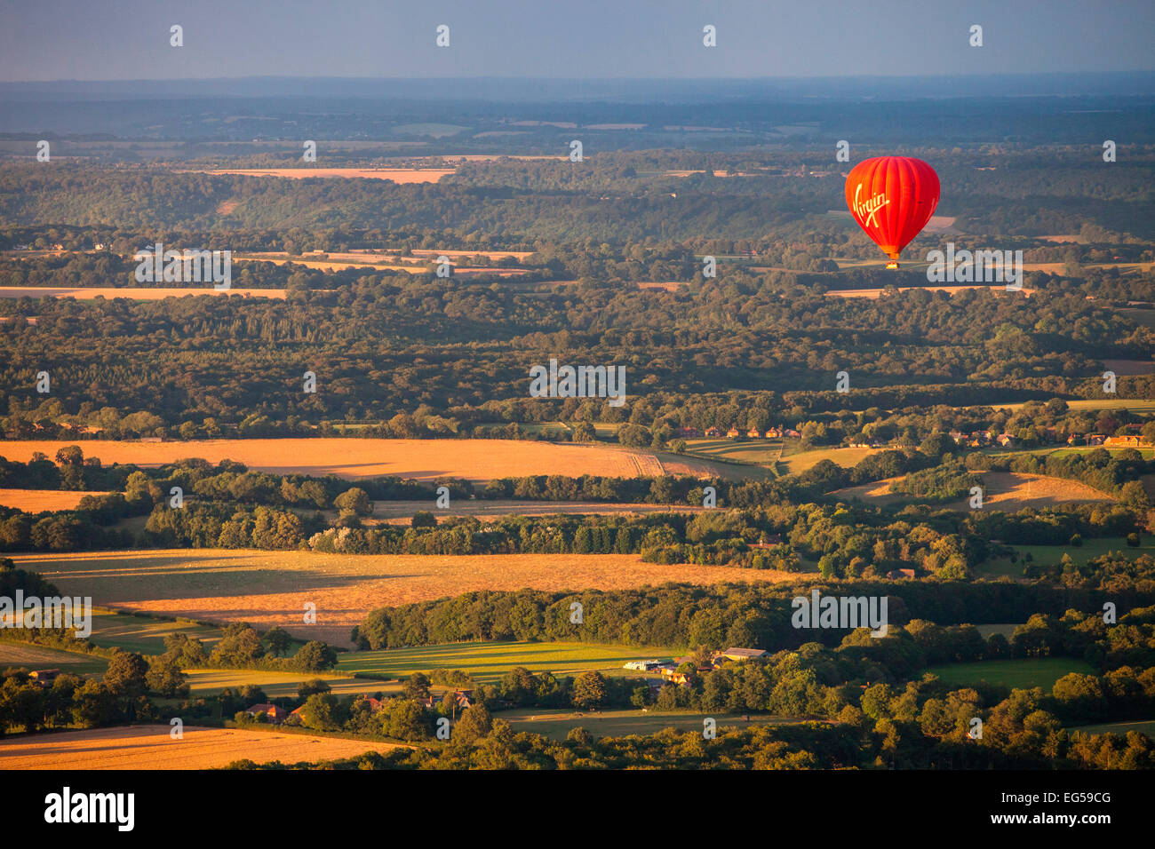 Red hot air balloon flying over rural landscape, South Oxfordshire, England Stock Photo