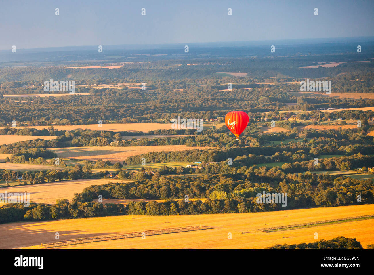 Red hot air balloon flying over rural landscape, South Oxfordshire, England Stock Photo