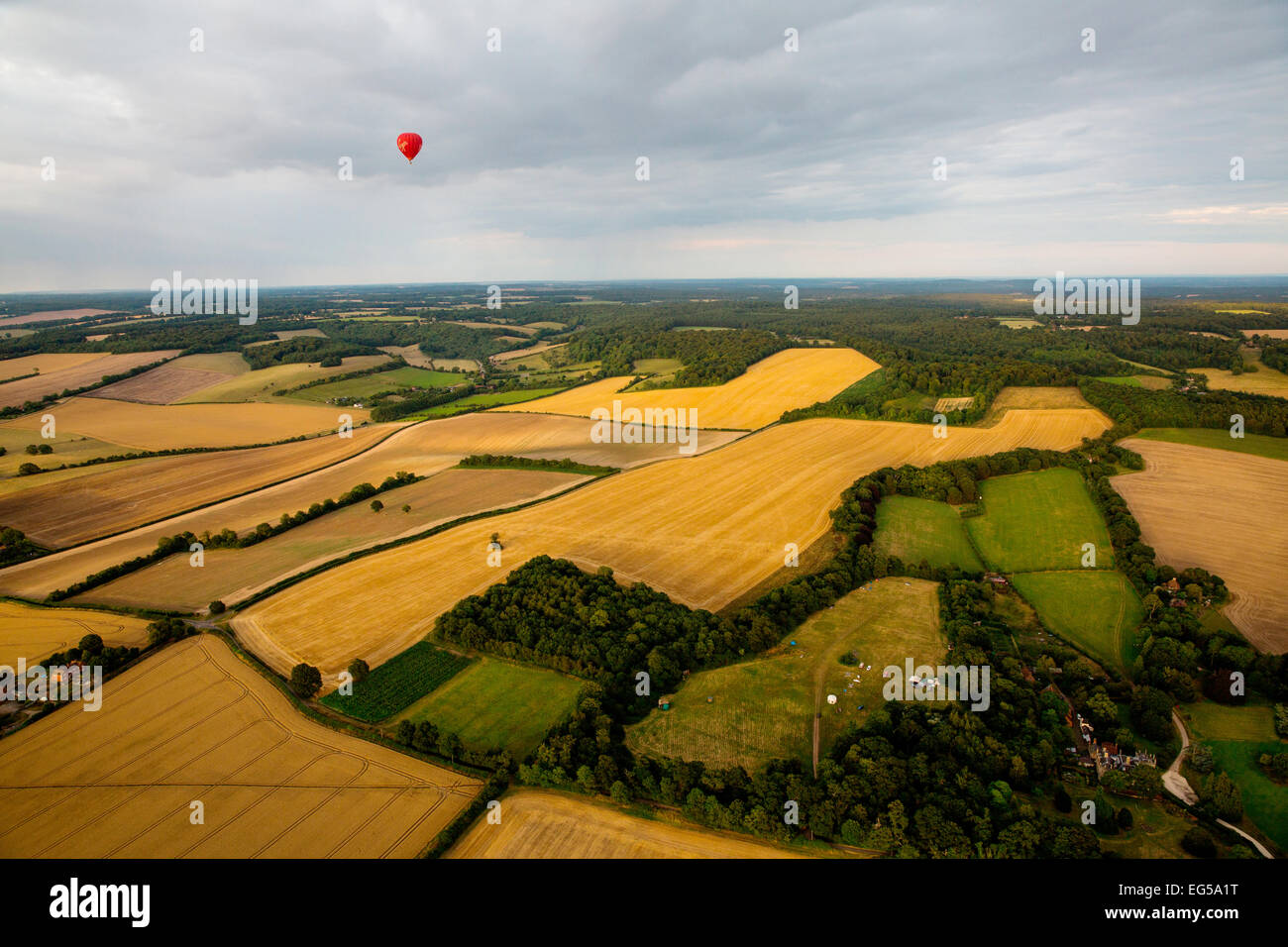 Distant view of red hot air balloon flying over rural landscape, South Oxfordshire, England Stock Photo