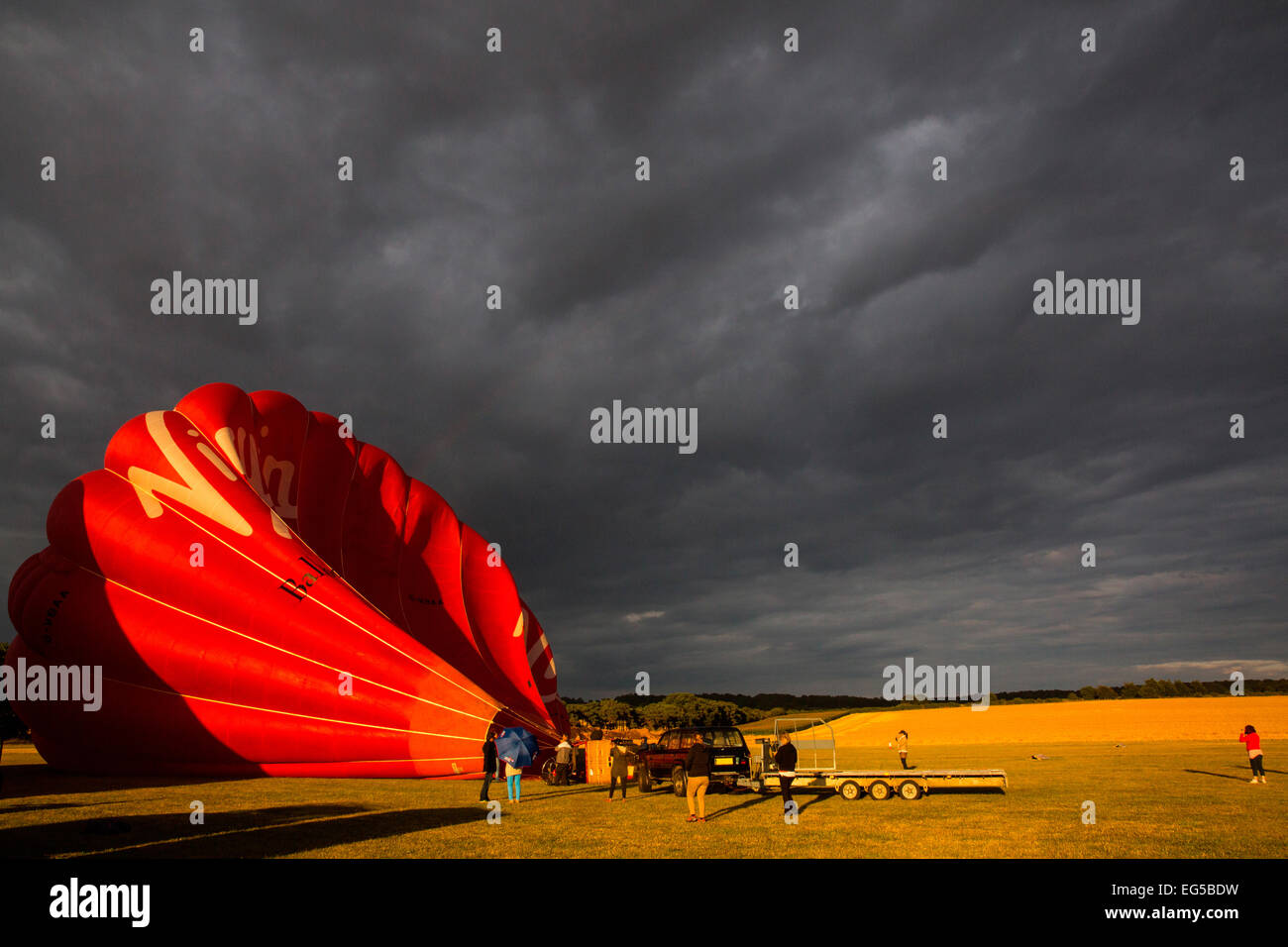 Teamwork preparation for tethered hot air balloon against dramatic sky, South Oxfordshire, England Stock Photo