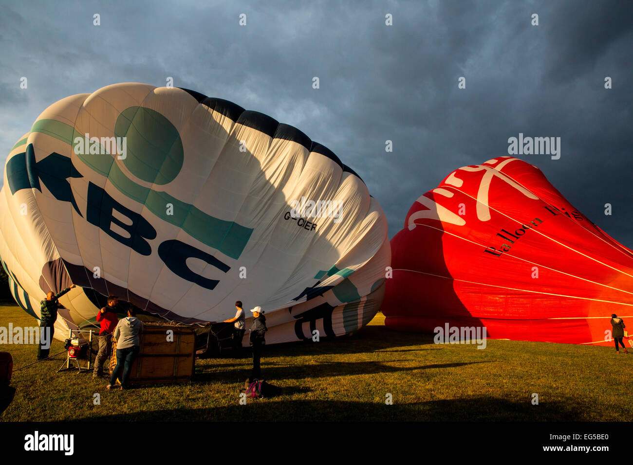 Teamwork preparation for tethered hot air balloons against dramatic sky, South Oxfordshire, EnglandHot air balloon Stock Photo