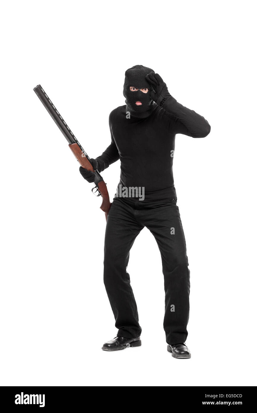 Full length portrait of a burglar with rifle looking through an imaginary glass isolated on white background Stock Photo