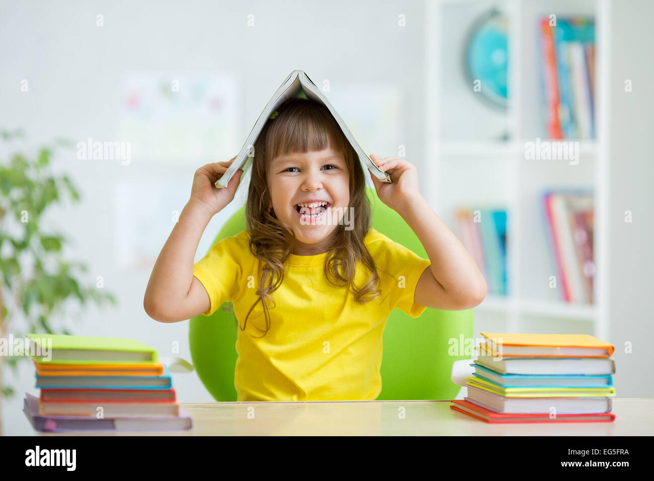 Student kid with a book over her head Stock Photo - Alamy