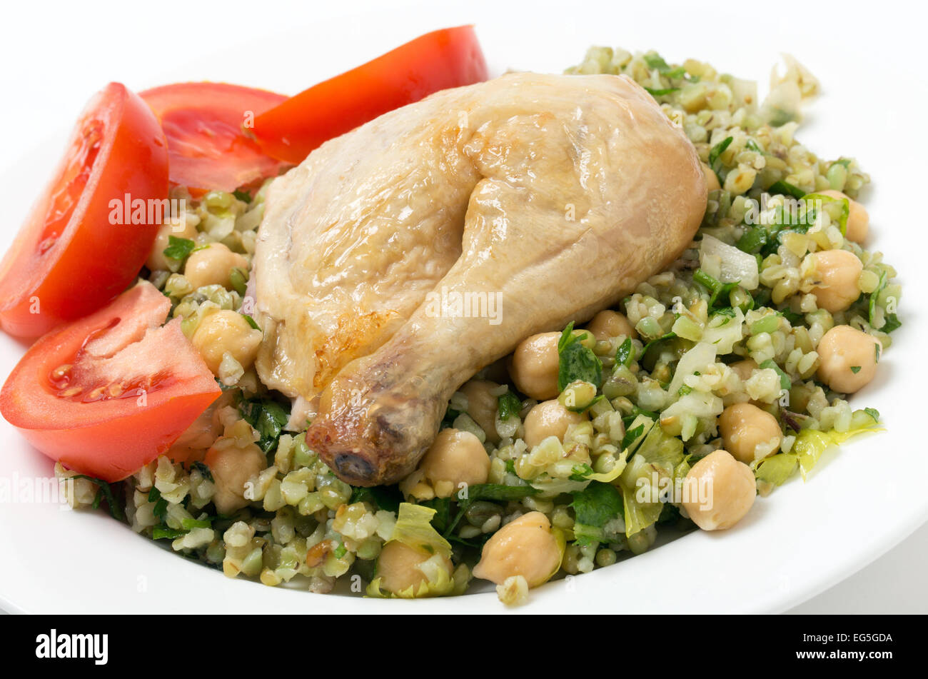 Freekeh salad with chickpeas, onion, parsley, celery, and a lemon juice and olive oil dressing, and a chicken leg with tomato Stock Photo