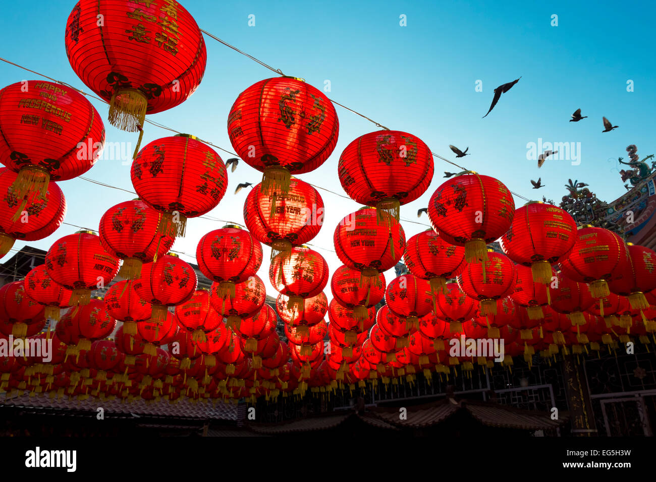 Chinese Lanterns over clear blue sky with birds flying Stock Photo